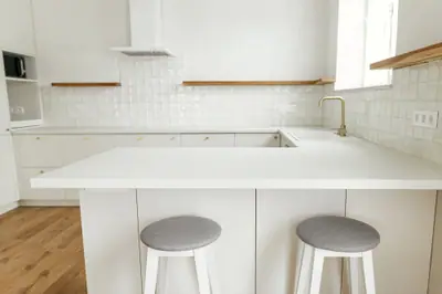 Cocina reformada con mobiliario blanco y encimera